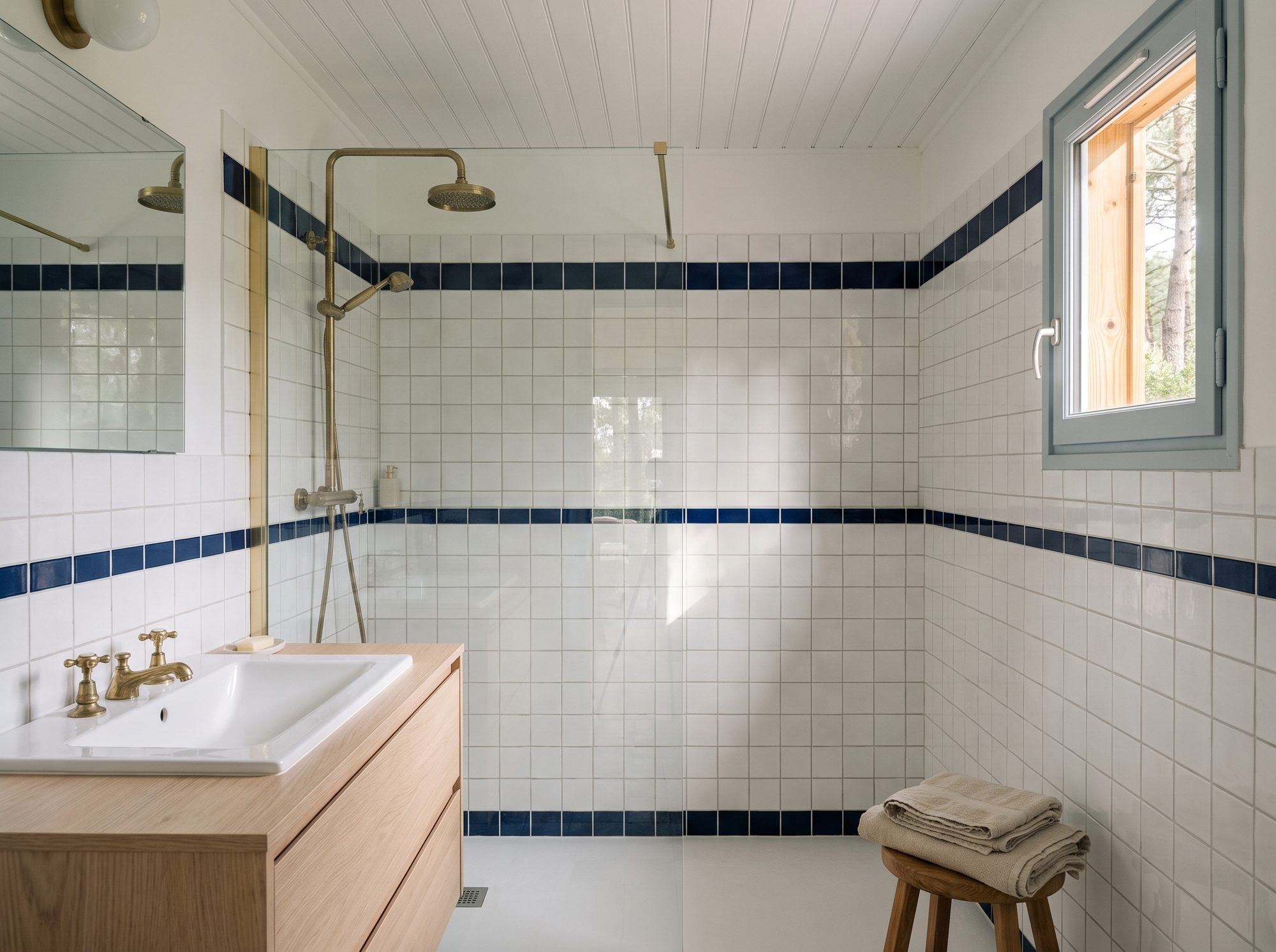 Salle de bains : carreaux blancs, liseré marine, laiton et chêne